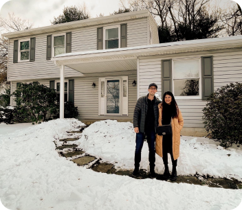 Couple standing in front of house with snow on the ground