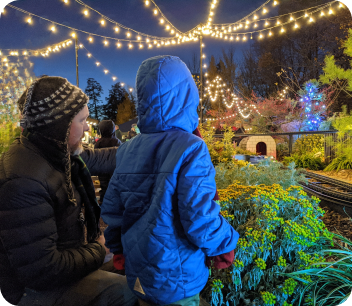 Child and man looking at train set and holiday lights